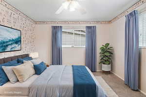 Owners suite bedroom with carpet flooring, a ceiling fan, and wallpapered walls