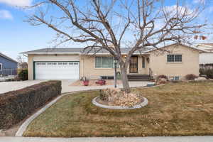 Single story home with brick siding, concrete driveway, an attached garage, and a front lawn