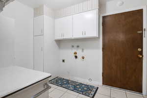 Main level laundry room with cabinet space, light tile patterned flooring, hookup for a washing machine, hookup for an electric dryer, and hookup for a gas dryer