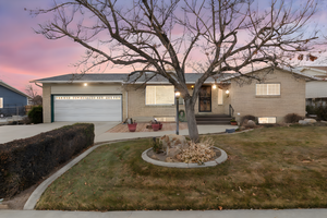 View of front of property with brick siding, concrete driveway, a garage, a front lawn, and a porch