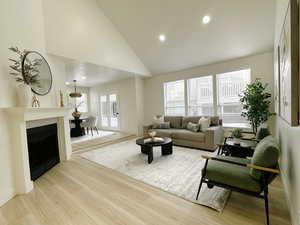 Living area featuring light wood-style flooring, recessed lighting, a fireplace, and high vaulted ceiling