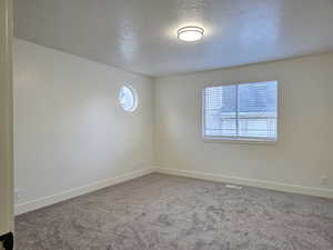 Unfurnished room with a textured ceiling and carpet flooring