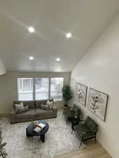 Living room with vaulted ceiling, wood finished floors, and recessed lighting