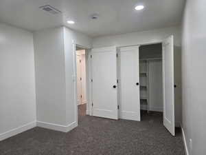Unfurnished bedroom with dark carpet, a closet, and recessed lighting