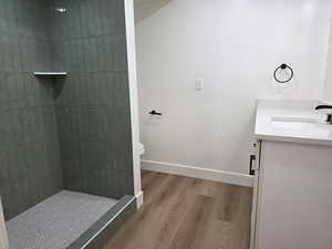 Full bath with vanity, tiled shower, and light wood-style floors