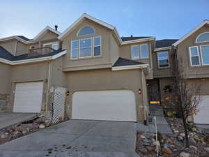View of front of house featuring stucco siding, concrete driveway, and an attached garage