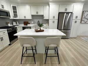 Kitchen with stainless steel appliances, white cabinets, light wood-style flooring, and recessed lighting