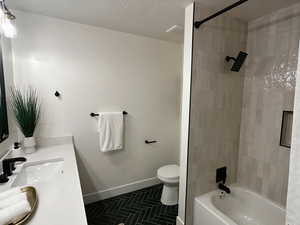 Full bath with vanity, bathtub / shower combination, dark tile patterned floors, and a textured ceiling