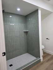 Full bathroom featuring tiled shower, wood finished floors, a textured ceiling, and recessed lighting