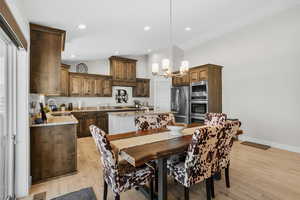 Dining space featuring light wood-style floors, a chandelier, high vaulted ceiling, and recessed lighting