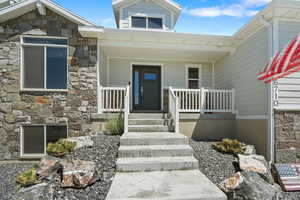 View of exterior entry with covered porch and stone siding