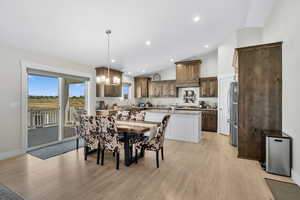 Dining space featuring lofted ceiling, light wood-style floors, a chandelier, and recessed lighting
