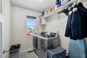 Laundry area with washing machine and clothes dryer and light tile patterned floors