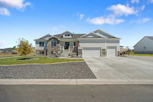 Craftsman house with stone siding, covered porch, a front lawn, driveway, and a garage