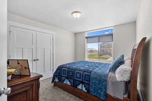 Bedroom with a textured ceiling, carpet flooring, and a closet