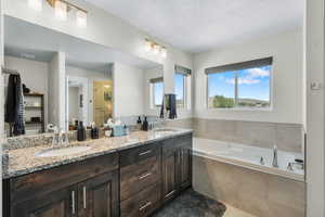 Full bathroom with double vanity, a garden tub, a stall shower, a textured ceiling, and tile patterned flooring