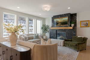 Living area with a high end fireplace, light wood-style floors, and recessed lighting