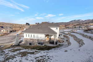 Snow covered house with a patio, stone siding, and a mountain view