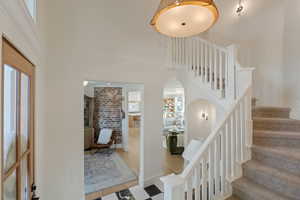 Stairs featuring arched walkways, a towering ceiling, and brick wall