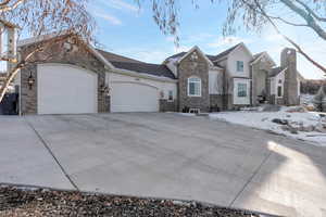 View of front facade featuring stone siding, an attached garage, and driveway