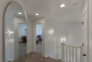 Hallway with recessed lighting, carpet flooring, and an upstairs landing