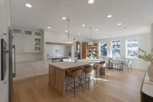 Kitchen with white cabinetry, pendant lighting, light wood finished floors, an island with sink, and recessed lighting