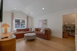 Living area with light wood finished floors, vaulted ceiling, and recessed lighting
