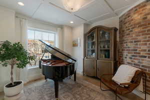 Sitting room with coffered ceiling, wood finished floors, brick wall, beamed ceiling, and recessed lighting