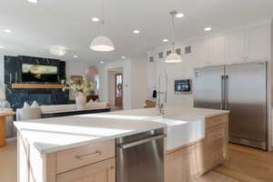Kitchen featuring appliances with stainless steel finishes, light brown cabinets, light wood finished floors, open floor plan, and recessed lighting