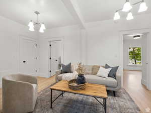 Living area featuring a chandelier, light wood finished floors, and beam ceiling
