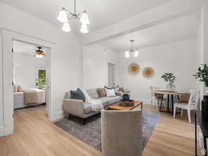 Living room featuring a chandelier, light wood finished floors, and ceiling fan