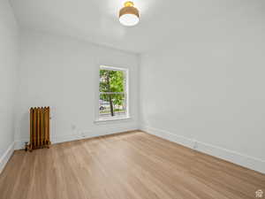 Unfurnished room with light wood-style flooring and radiator