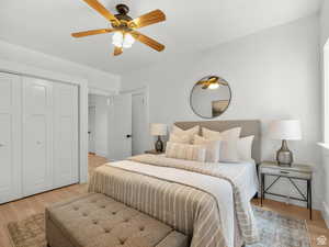 Bedroom with light wood-type flooring, ceiling fan, and a closet
