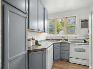 Kitchen featuring gray cabinetry, white appliances, dark countertops, light wood-style floors, and a wall mounted AC