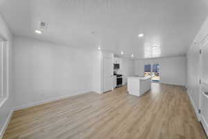 Unfurnished living room featuring light wood finished floors, recessed lighting, and a textured ceiling
