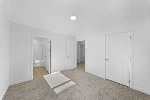 Unfurnished bedroom featuring light carpet and connected bathroom