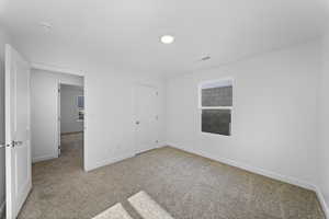 Unfurnished bedroom featuring light carpet and baseboards