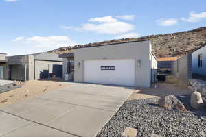 Contemporary house featuring stucco siding, a mountain view, driveway, and an attached garage