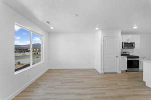 Kitchen featuring white cabinetry, stainless steel appliances, light wood-type flooring, a mountain view, and recessed lighting