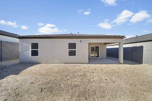 Rear view of house with a fenced backyard, stucco siding, and a patio area