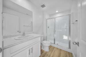 Full bath featuring a shower stall, vanity, and light wood-style flooring
