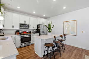 Kitchen featuring appliances with stainless steel finishes, white cabinets, a center island, and recessed lighting