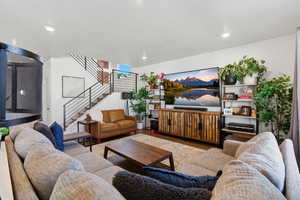 Living room featuring wood finished floors, stairway, a textured ceiling, and recessed lighting