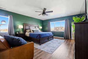 Bedroom with light wood-style floors, ceiling fan, and a textured ceiling