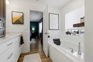 Bathroom with vanity, dark wood-style floors, a garden tub, and ensuite bathroom