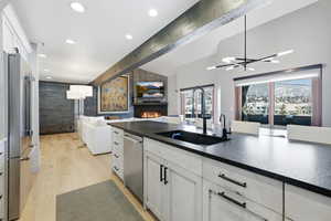 Kitchen featuring open floor plan, white cabinetry, a fireplace, appliances with stainless steel finishes, and recessed lighting