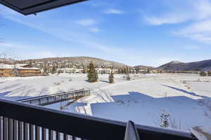 Snowy yard with a mountain view and a balcony