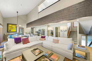 Living area with high vaulted ceiling and stairs