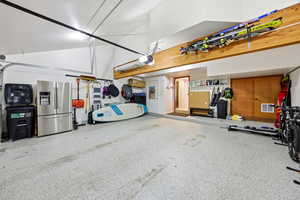 Garage with stainless steel fridge and a garage door opener