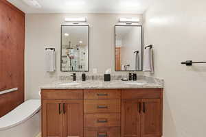 Bathroom featuring double vanity, walk in shower, and a textured wall